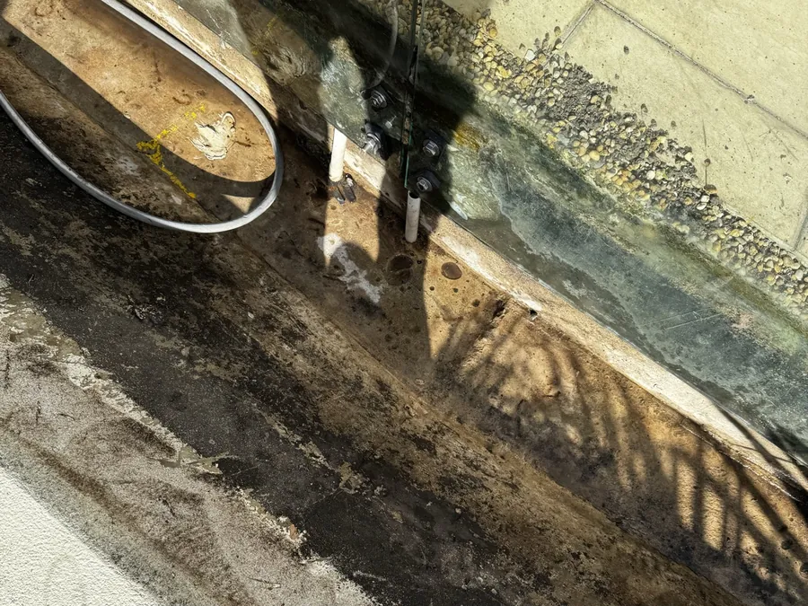 Narrow trench beside a wall with an exposed line